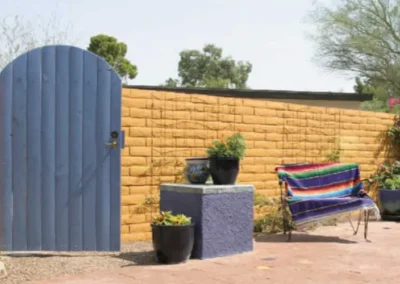 Charming Backyard Featuring Blue Gate And Warm Yellow Stucco Wall