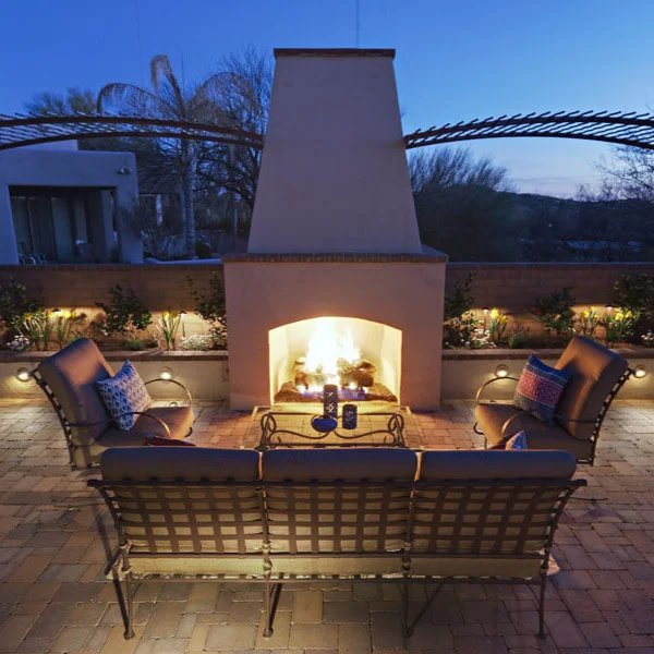 Outdoor fireplace with seating area at dusk in landscaped backyard Outdoor fireplace with seating area at dusk in landscaped backyard