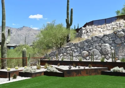 Tiered Steel Planters Filled With Desert Succulents And Cacti On Artificial Turf, Set Against A Rocky Hillside With Saguaros And Mountain Views In Tucson