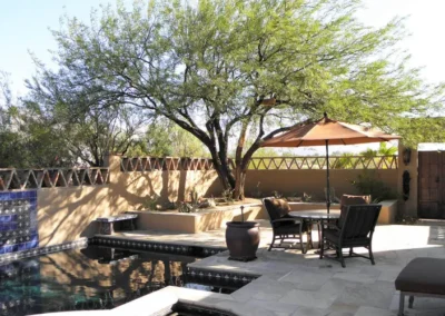 Backyard pool with large tree, umbrella seating, and landscaped patio