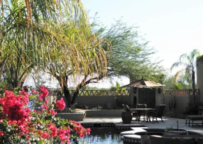 Backyard pool landscaping with flower garden, palm trees, and outdoor seating area