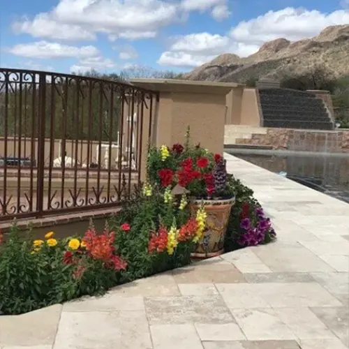 Backyard patio with stone pavers, black metal fence, and colorful flower beds in Tucson desert setting Backyard patio with stone pavers, black metal fence, and colorful flower beds in Tucson desert setting