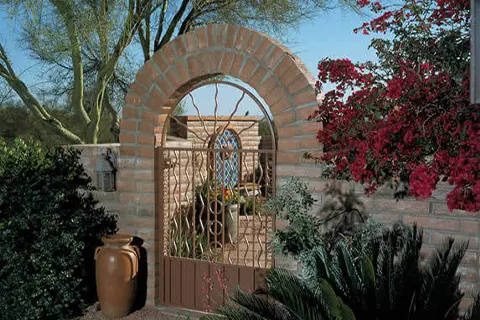 Brick garden arch with decorative entry gate and plants