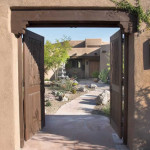 Wooden gates at masonry entry arch with flagstone path